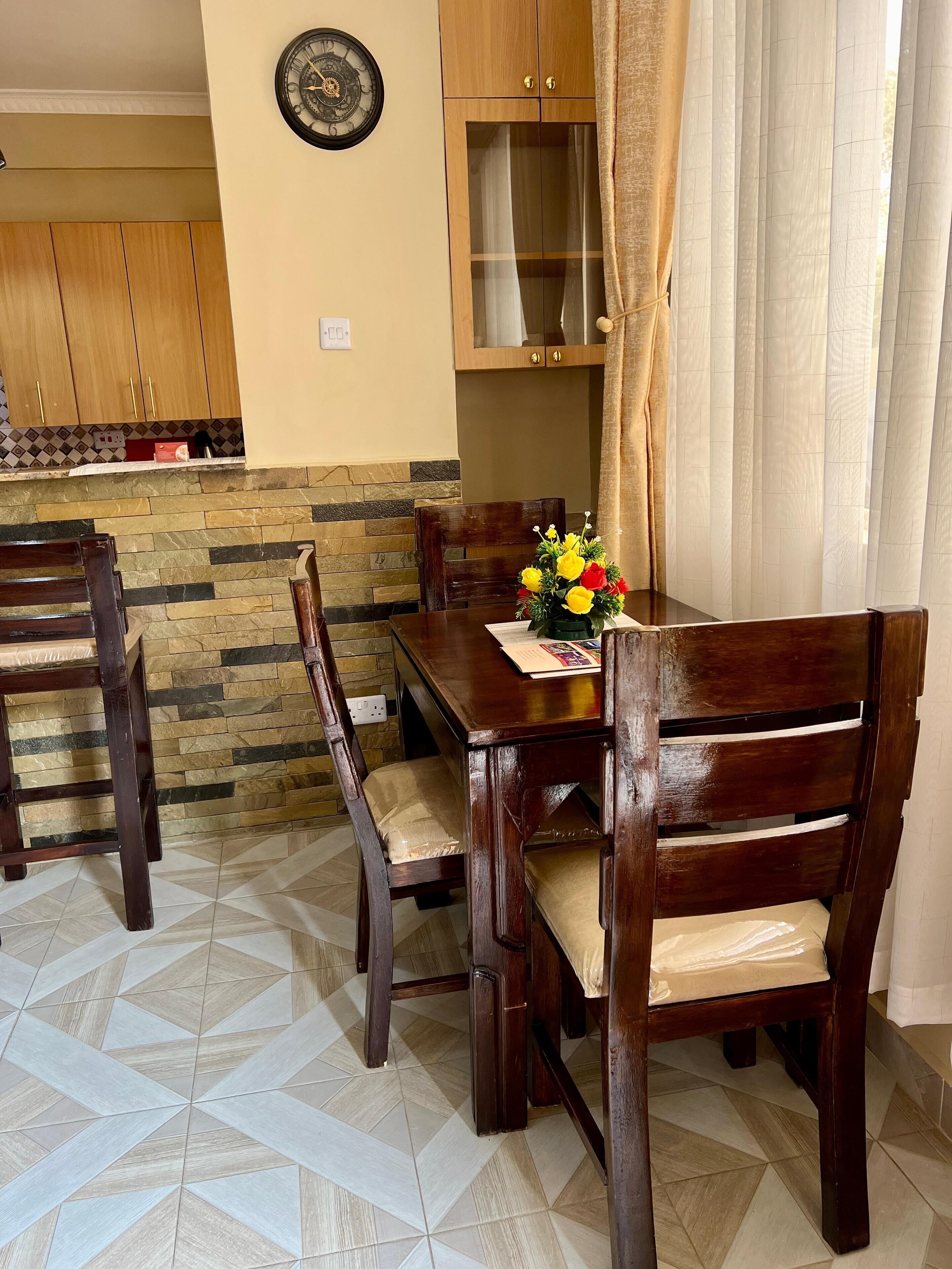 Un comedor con una mesa y sillas de madera, un revestimiento de pared de piedra y un armario de madera al fondo.