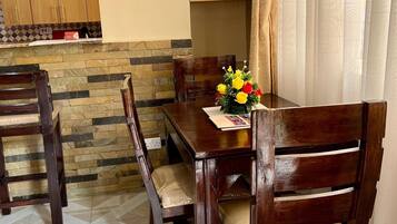 Un comedor con una mesa y sillas de madera, un revestimiento de pared de piedra y un armario de madera al fondo.