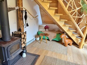 A cozy cabin interior with a wood-burning stove, a wooden staircase, and rustic decor. - Magic Mushroom A-Frame Cabin with wood-burning hottub (Sunshine Valley)