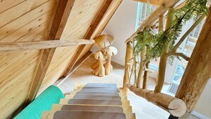 A wooden staircase with a natural design, leading to a room with a view of the outside.