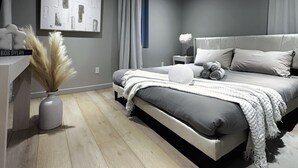 Une chambre à coucher moderne avec un lit, une table de chevet et une œuvre d’art accrochée au mur.