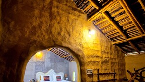 Una habitación rústica con una cama, una escalera de madera y un muro con superficie texturizada.