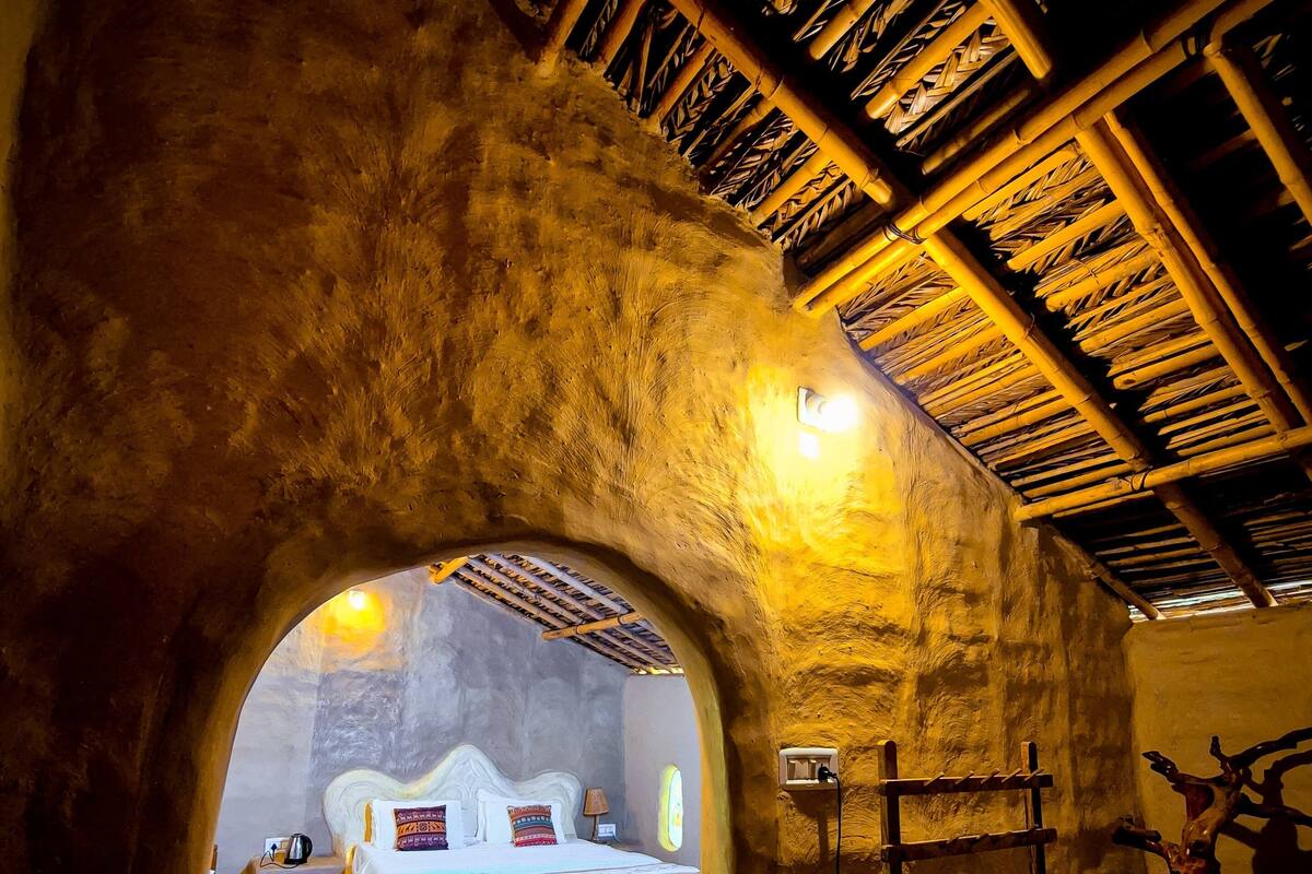 Una habitación rústica con una cama, una escalera de madera y un muro con superficie texturizada.