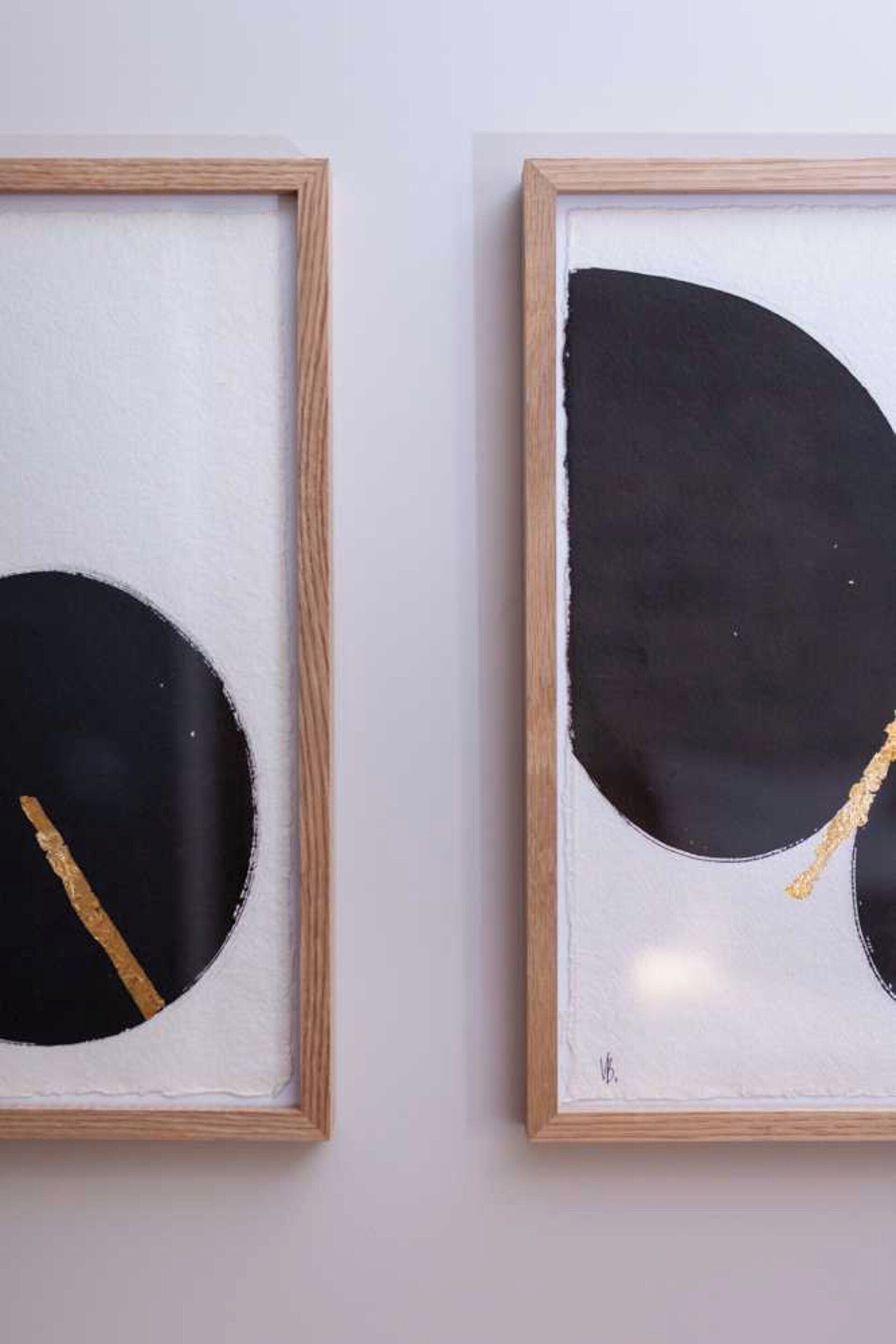 Deux œuvres d’art encadrées aux motifs abstraits, accrochées à un mur uni.