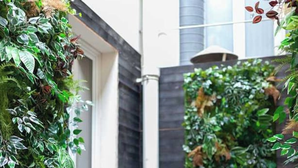 A modern outdoor area with a wooden deck, a vertical garden, and a small seating area. - Hotel Tinah: Elegance and Comfort Near the Champs-elysees (Paris)