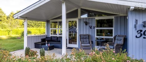 A covered outdoor seating area with a sofa, chairs, and a table.
