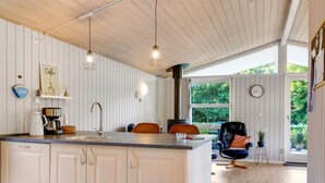 A modern kitchen with white cabinetry, a large island, pendant lights, and a view of the outdoors through large windows. - "Dorethea" - 30km from the sea by Interhome (Toftlund)