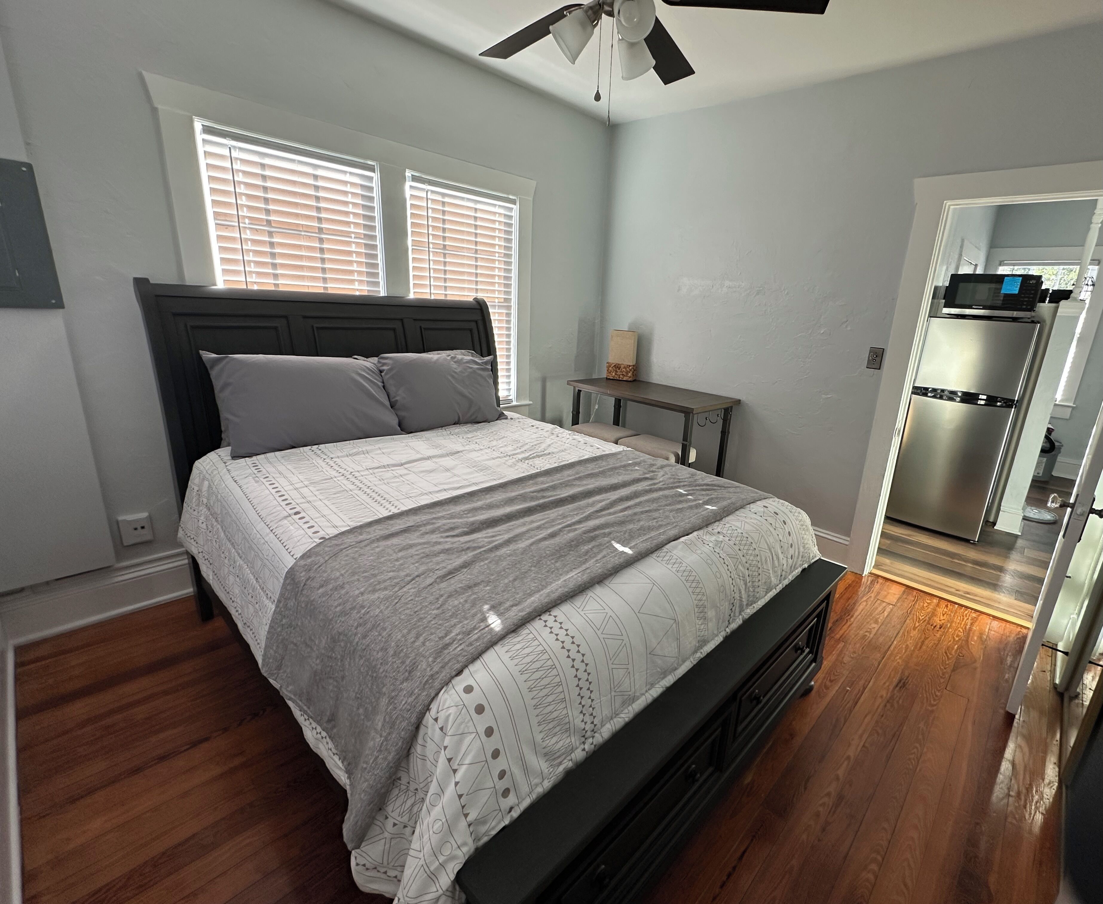 A bedroom with a bed, bedside table, and a view into the kitchen.