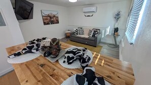 A living room with a wooden floor, a grey sofa, and a large painting of a bull.