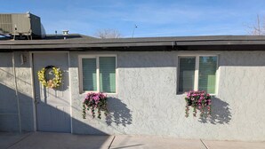 A single-story house with a concrete driveway, a garage door, and two windows with hanging flower baskets.