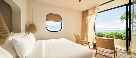 Un dormitorio con una cama grande, una ventana con vistas, un ventilador de techo y una silla junto a la ventana.