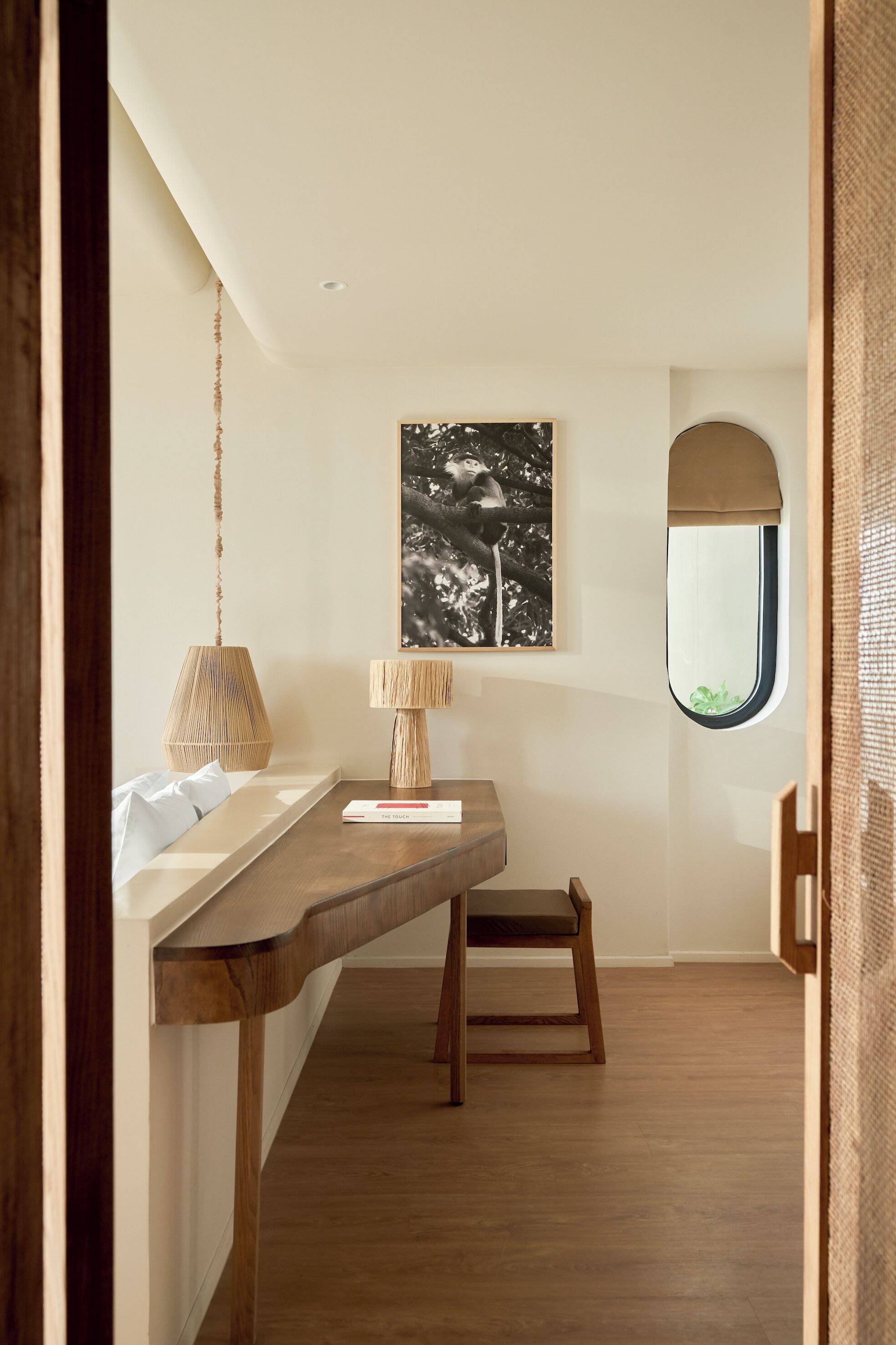 Ein Zimmer mit einem Holztisch, einer Pendelleuchte, einem gerahmten Bild an der Wand und einem Fenster mit Blick.
