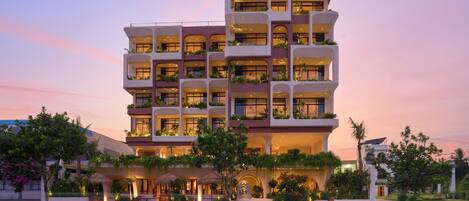 A multi-story hotel with balconies, outdoor seating, and lush landscaping.