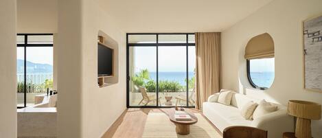 A spacious living room with a large sliding glass door leading to a balcony with a view of the sea.