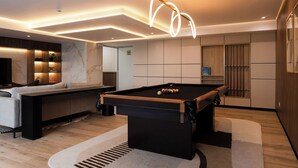Een moderne woonkamer met een pooltafel, een bank en een televisie.
