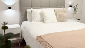 Een netjes opgemaakte slaapkamer met een bed, nachtkastjes en een bijpassend nachtkastje.