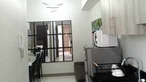 A compact kitchen with a dining area, a refrigerator, a microwave, and a hanging light fixture.