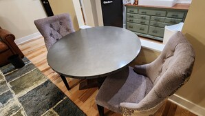 Un coin repas avec une table ronde et deux chaises rembourrées.