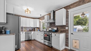 Una cocina moderna con armarios blancos, un refrigerador de acero inoxidable, un horno doble y una pared decorativa de madera.