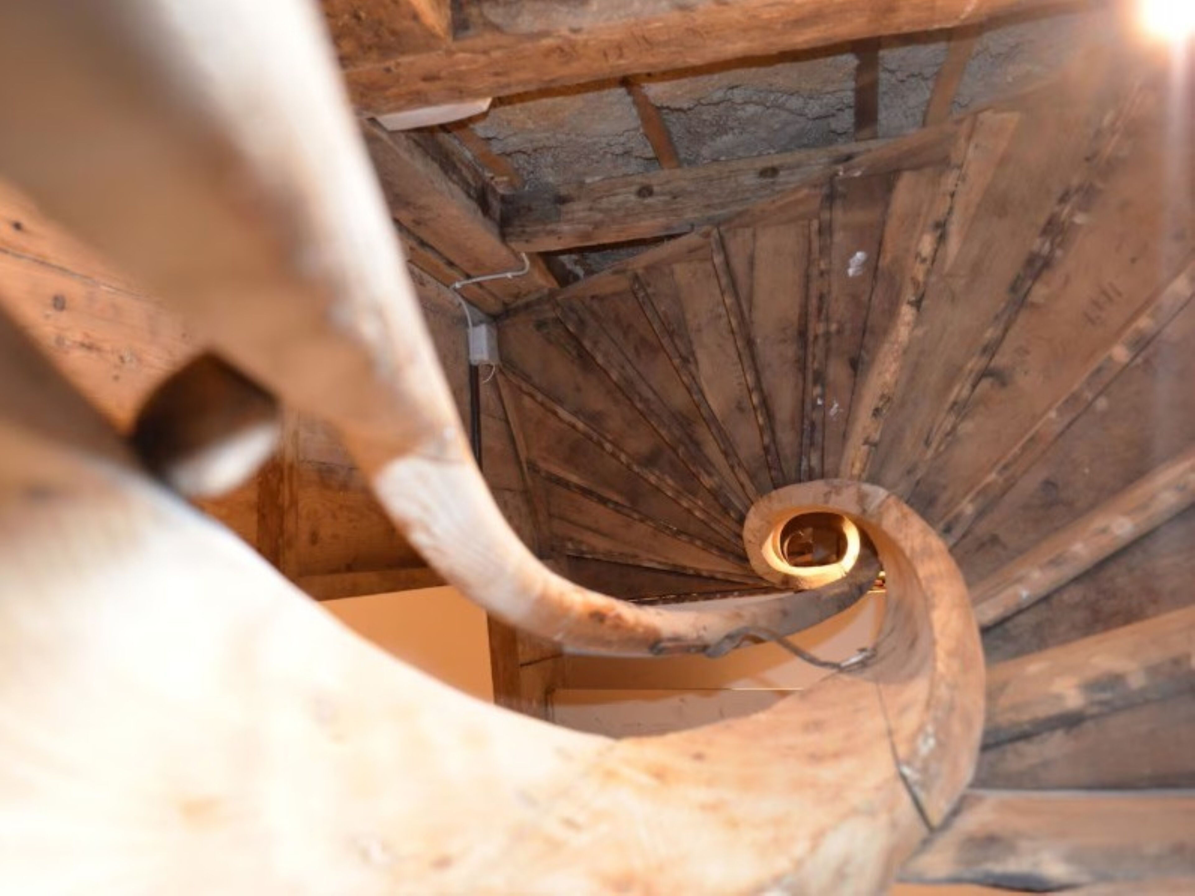 Eine Wendeltreppe mit Holzbodenstufen und einem Metallgeländer.