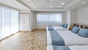 Habitació d'hotel amb un llit gran, un armari i una finestra amb cortines transparents.