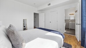 A bedroom with a large bed, a mirror, and a bathroom visible through an open door.
