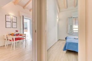 Un dormitorio moderno con una cama, un ventanal y una puerta que da a un comedor.