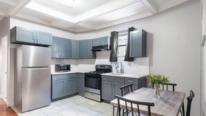 A modern kitchen with grey cabinets, stainless steel appliances, and a dining area with a table and chairs.
