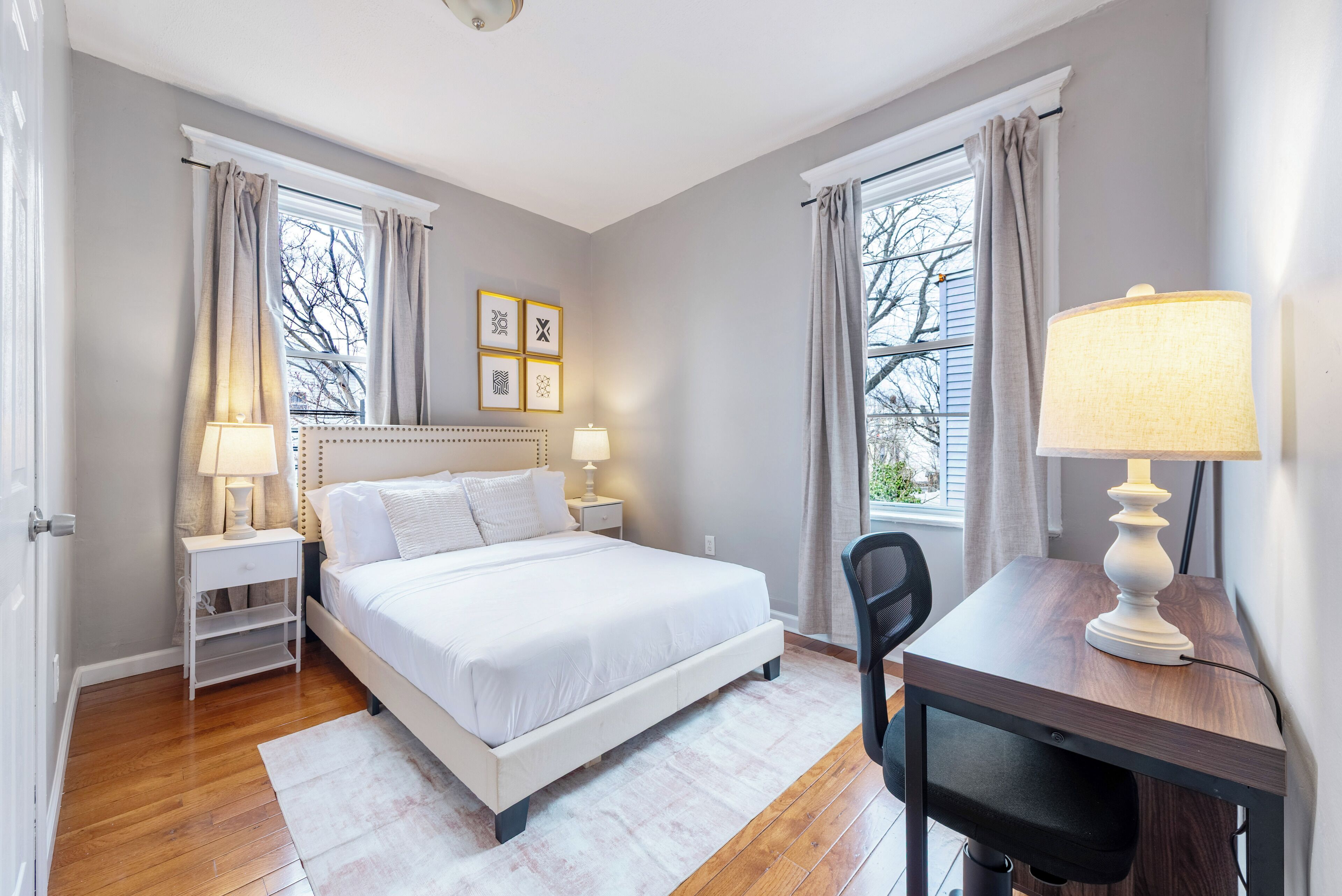 A bedroom with a bed, bedside tables, a desk, and a chair.