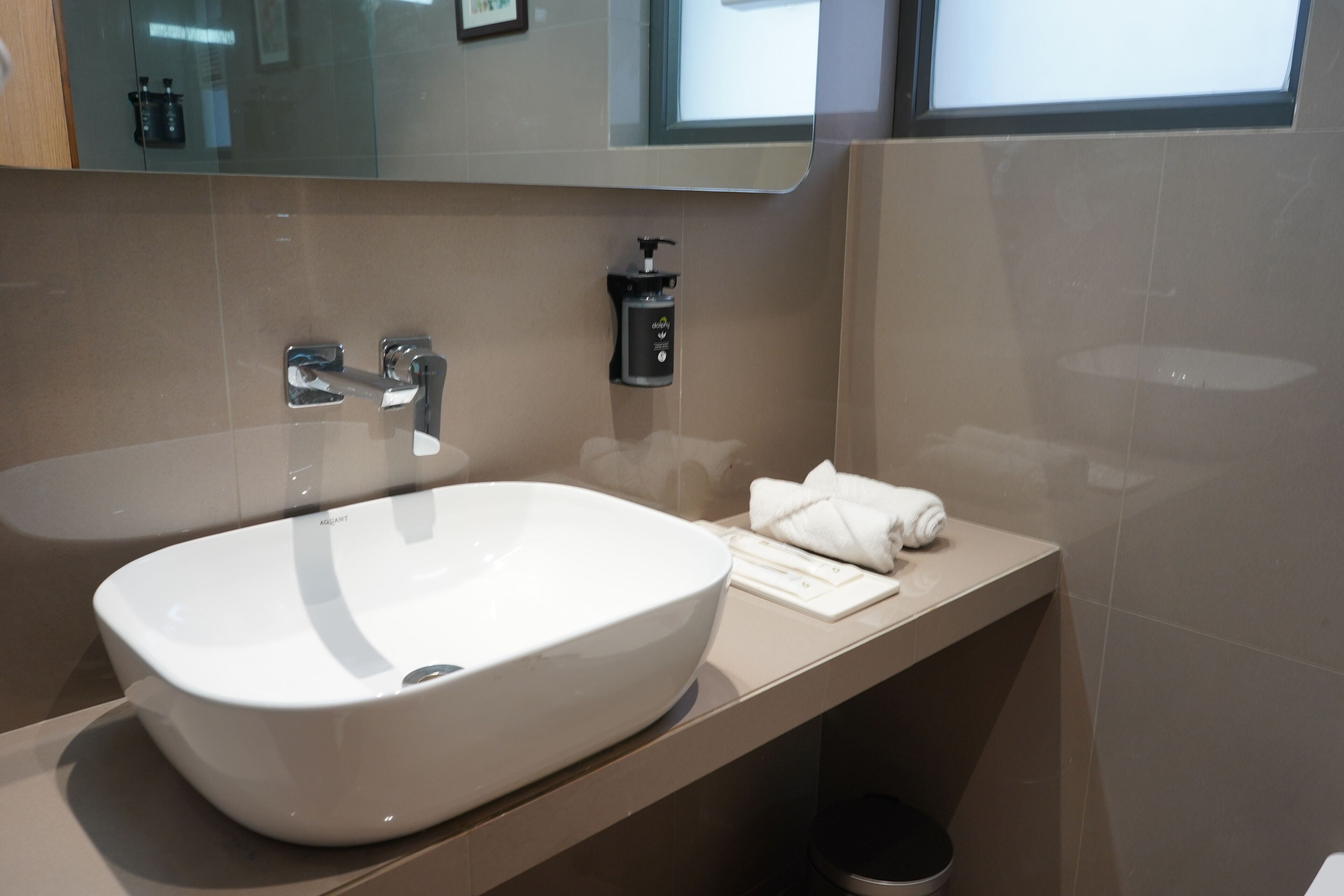 A modern bathroom with a large white sink, a mirror, and a towel rack.