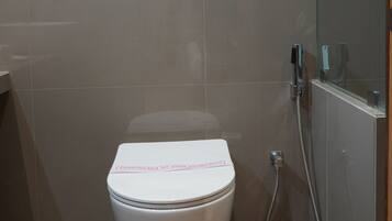 Une salle de bain moderne avec des toilettes, une œuvre d’art florale encadrée au mur et une cabine de douche en verre.
