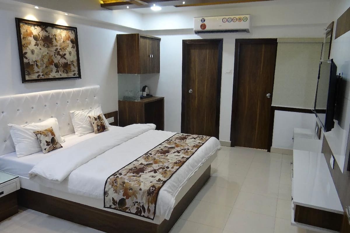 Een moderne slaapkamer met een groot bed, een nachtkastje, een dressoir, een spiegel en een plafondventilator.