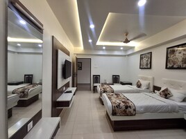 A hotel room with two beds, a TV mounted on the wall, a ceiling fan, and a door leading to another room.
