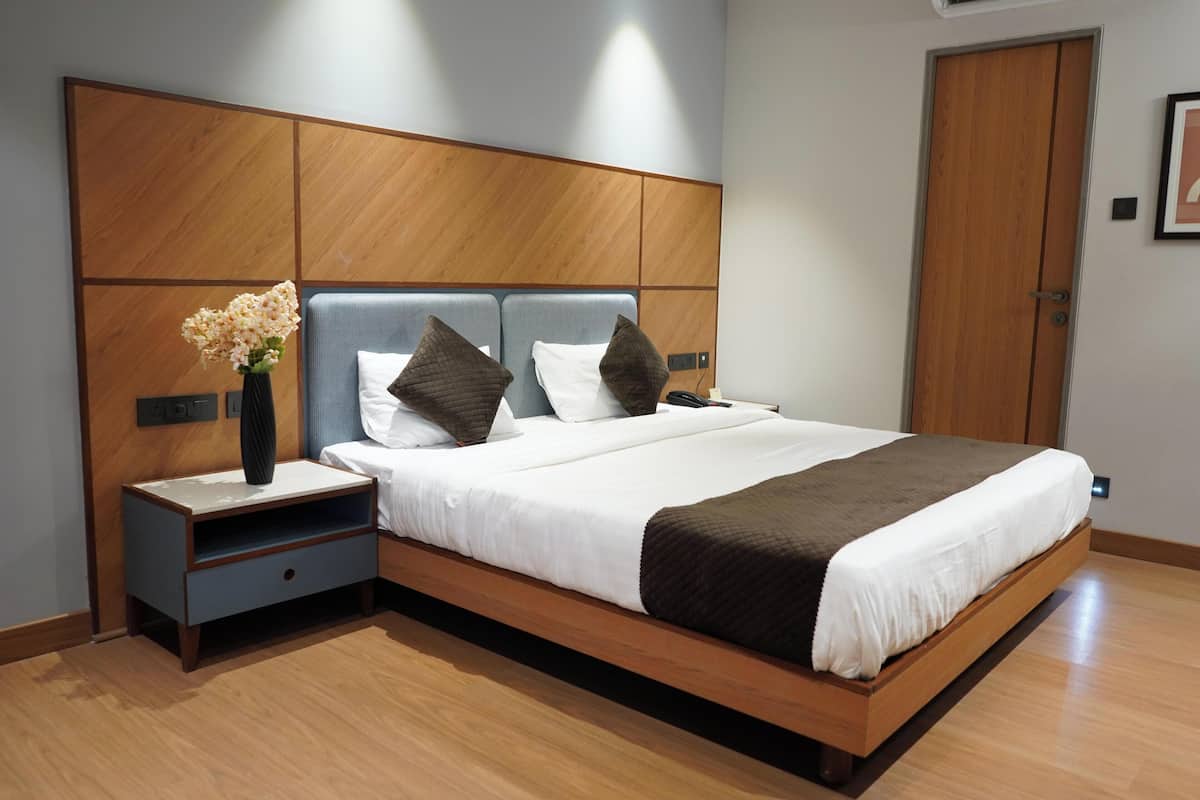Een moderne slaapkamer met een houten hoofdbord, nachtkastje en een groot bed met een bruine plaid.