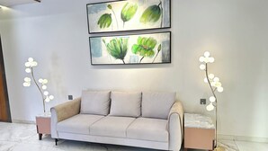 Een moderne woonkamer met een beige bank, twee lijstwerken en twee vloerlampen.