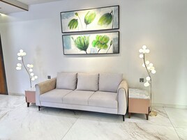 A modern living room with a beige sofa, two framed paintings, and two floor lamps.