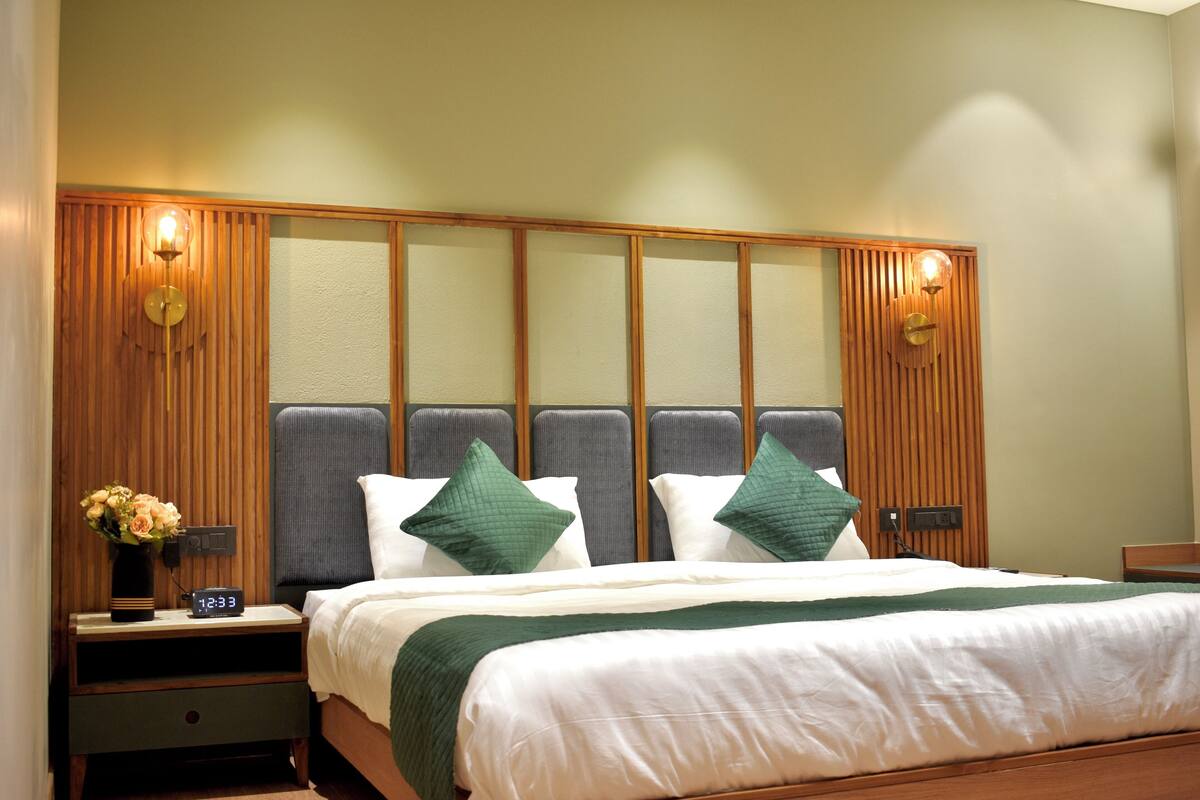 Een hotelkamer met een bed, nachtkastje en wandlampen.