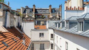 Una calle estrecha flanqueada por edificios con techos de tejas de arcilla, fachadas blancas y numerosas chimeneas.