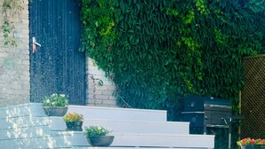 Un espace extérieur moderne agrémenté d’un escalier en béton, de plantes en pot et d’une pelouse.
