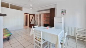 A spacious room with a dining table, chairs, a ceiling fan, a refrigerator, and a small kitchenette area. - Casa Francesca near center and beach (Porto Azzurro)