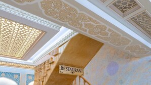 A wooden staircase with a sign indicating a restaurant. - Grand Vizir hotel (Khiva)