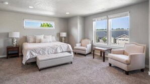 A bedroom with a bed, two armchairs, a small table, and a window with a view of houses. - Fantastic High Desert Retreat, Pet Friendly, Fenced Backyard w/ Covered Patio, Ping Pong, BBQ (Bend)