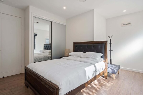 Un dormitorio con una cama grande, un armario, un espejo y un perchero.