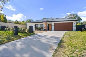 Une maison moderne à deux étages, dotée d’un garage, d’une allée et d’une pelouse bien entretenue.