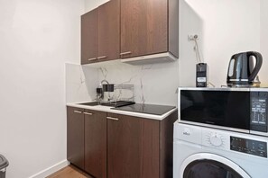 Una cocina compacta con microondas, cafetera y lavadora.