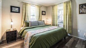 A bedroom with a bed, curtains, a nightstand, a lamp, and a picture on the wall. - Fun-ViBe-Hot-Tub-Oasis, Walk to Downtown, Pets OK (Boise)
