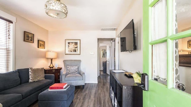 A modern living room with a sofa, armchair, ottoman, and a television mounted on the wall. - Fun-ViBe-Hot-Tub-Oasis, Walk to Downtown, Pets OK (Boise)