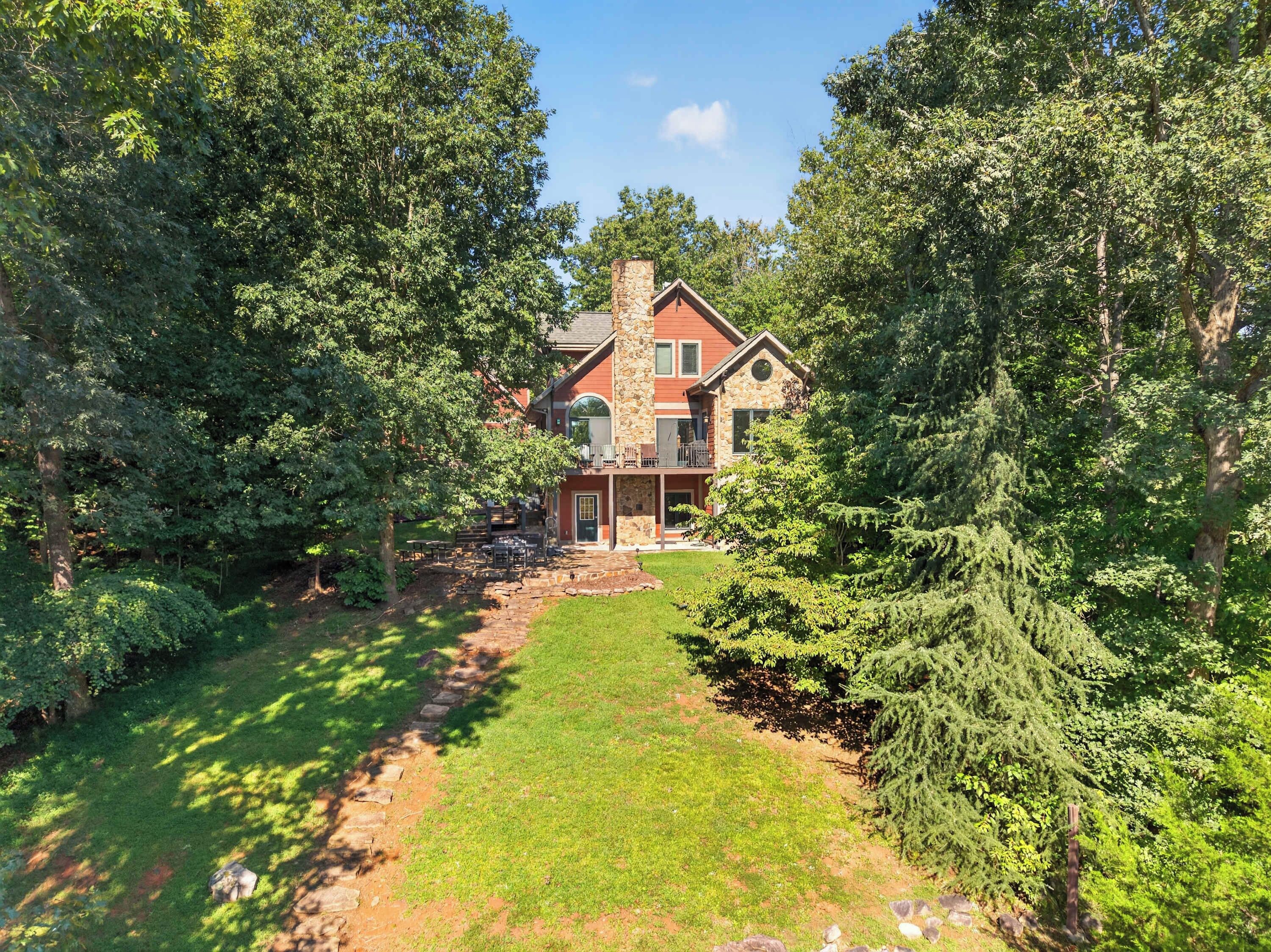 A two-story stone house with a stone chimney, a front porch, and a well-maintained lawn.