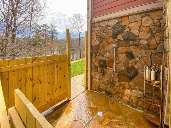 A stone shower with a wooden fence and a stone wall.