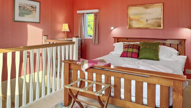 A bedroom with a bed, a window with curtains, a wooden bench, and a railing. - The Annex at Mains House (Tain)
